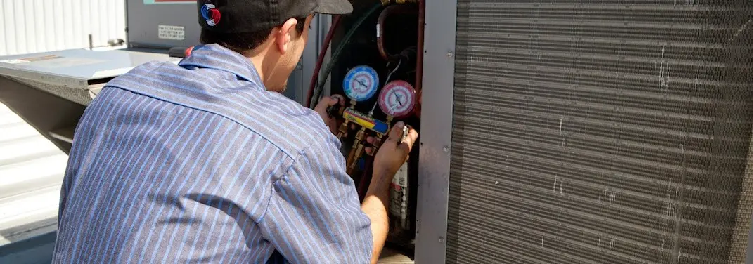 HVAC technician servicing a condenser unit in Lake San Marcos